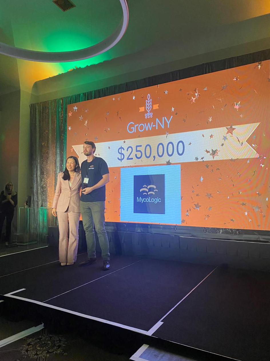 Chris Cornelison on stage beside a screen reading Grow-NY $250,000 MycoLogic