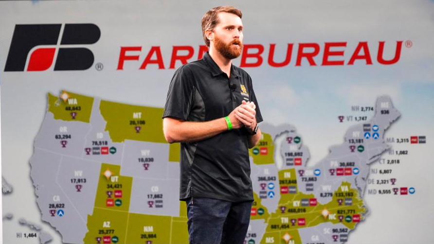 Chris Cornelison presenting on stage in front of a Farm Bureau backdrop map of the United States